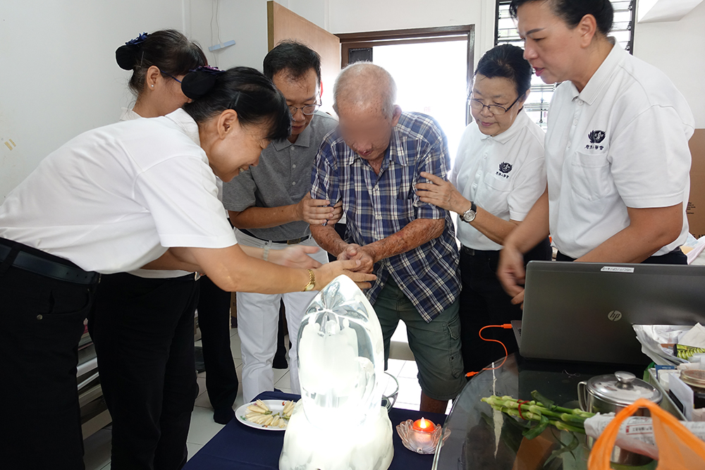 唐阿公在医护人员和志工协助下，完成“礼佛足、接花香、祝福吉祥”的浴佛仪式。